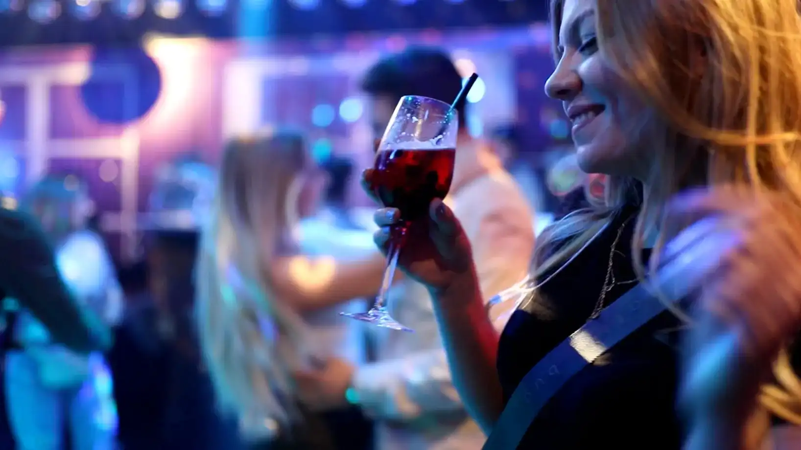 Frau mit Drink lächelnd im Club
