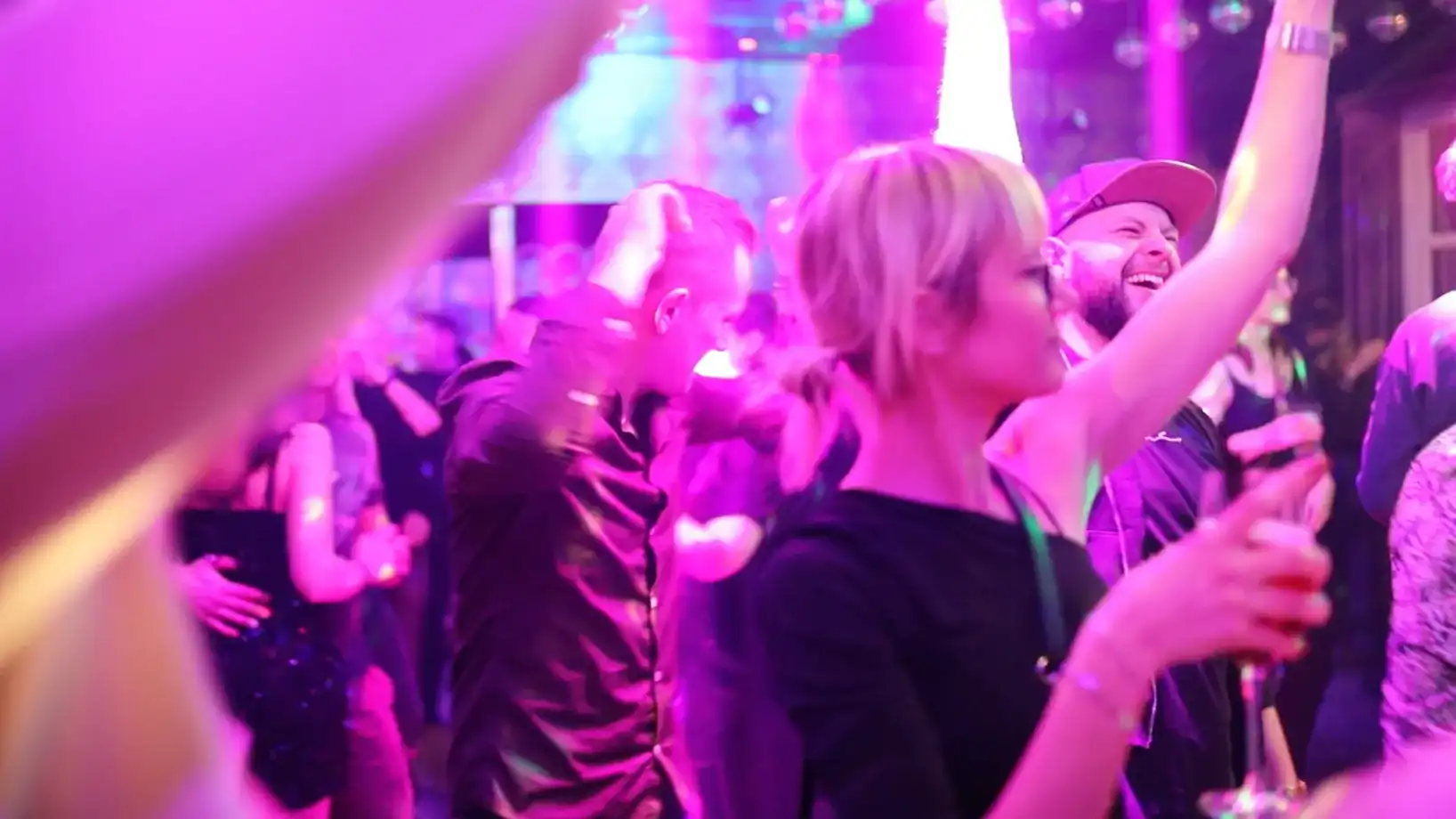 Menschen tanzen in pink-lila Lichtstimmung