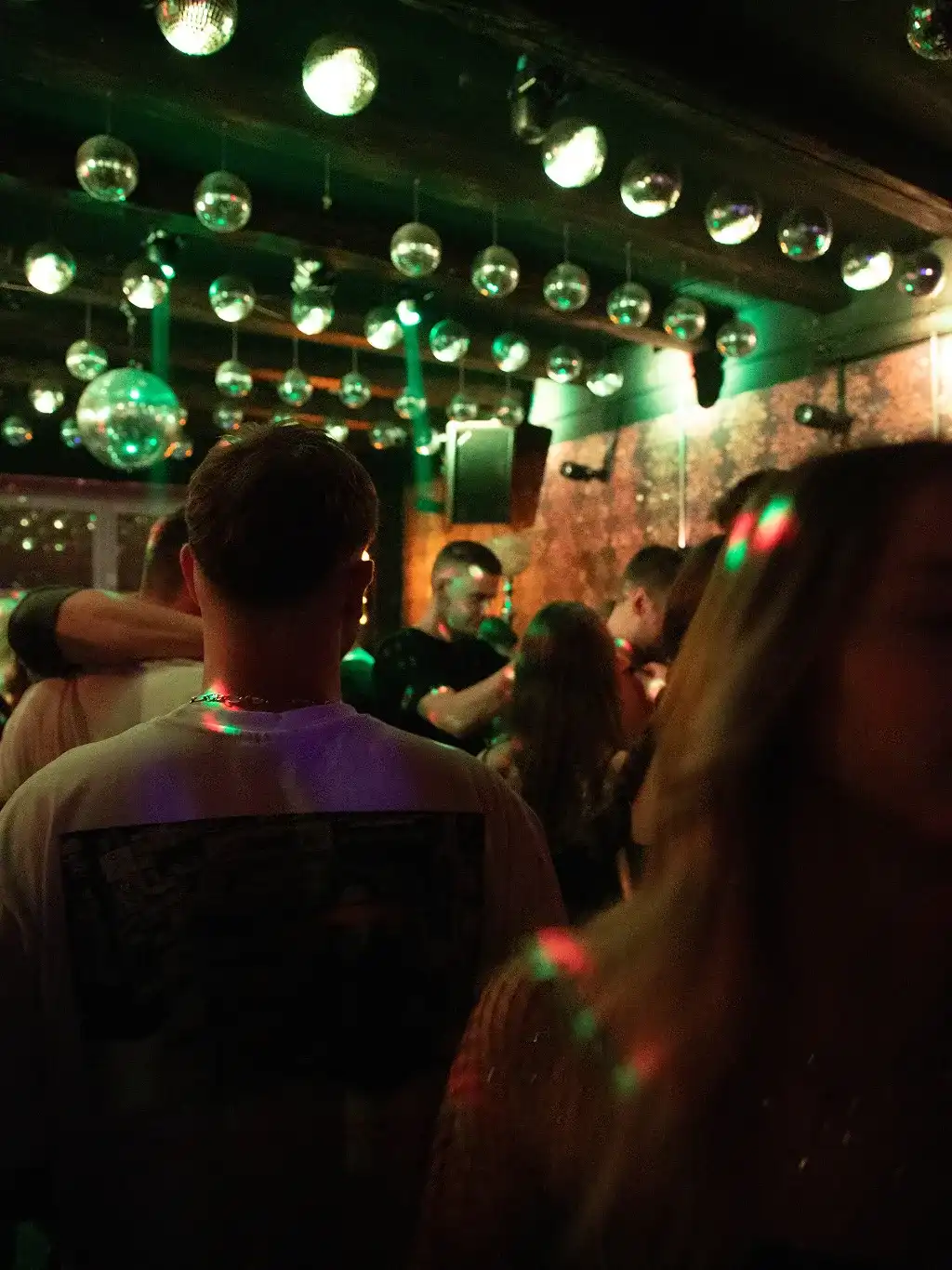 Partycrowd unter grünen Spotlights und Diskokugeln