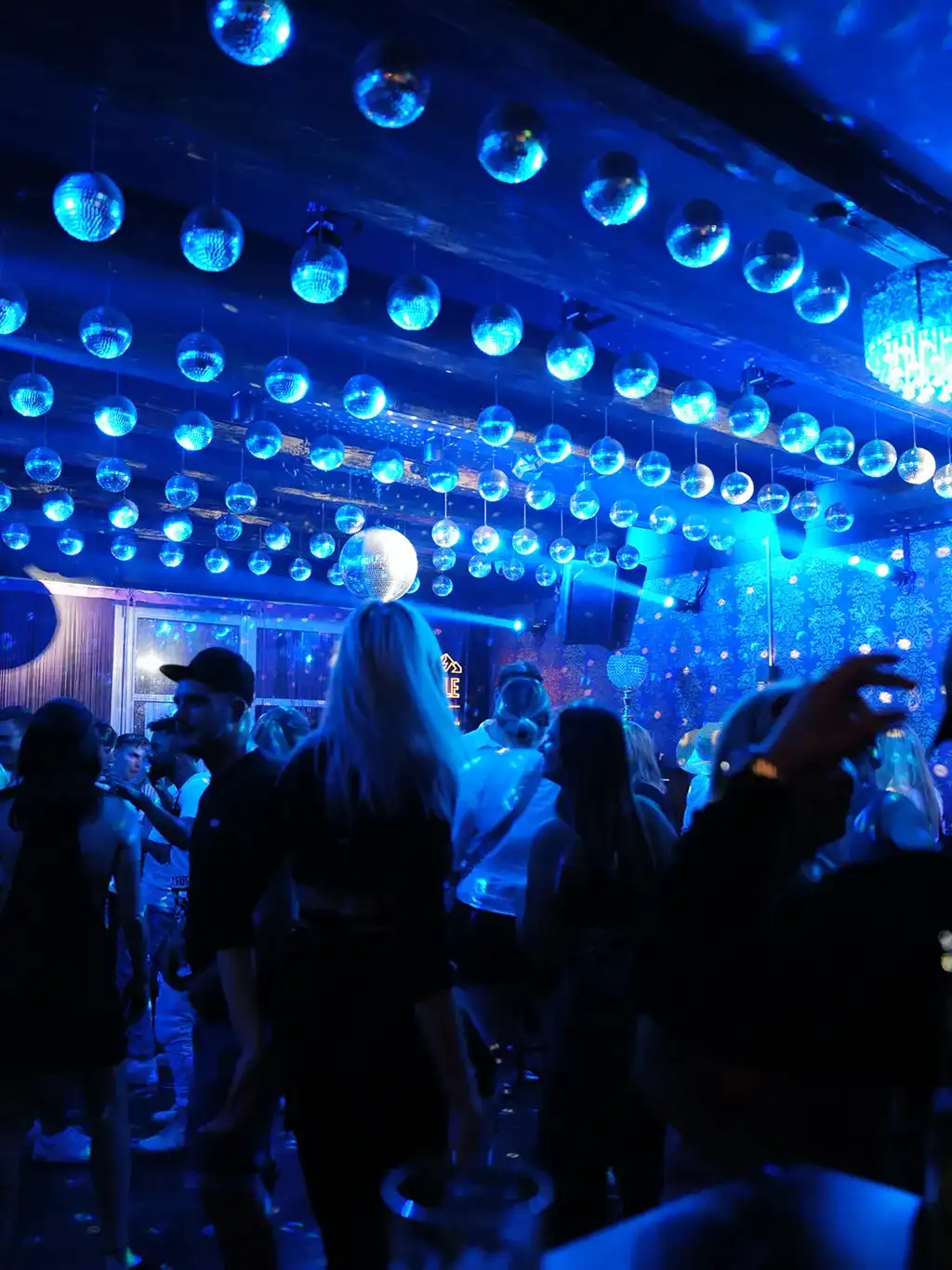 Tanzfläche im blauen Licht, viele Diskokugeln an der Decke