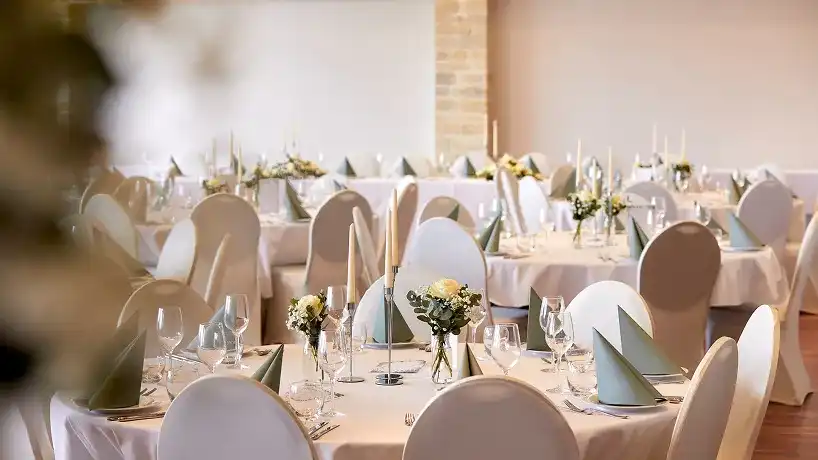 Runde Tische mit Kerzen und Blumengestecken