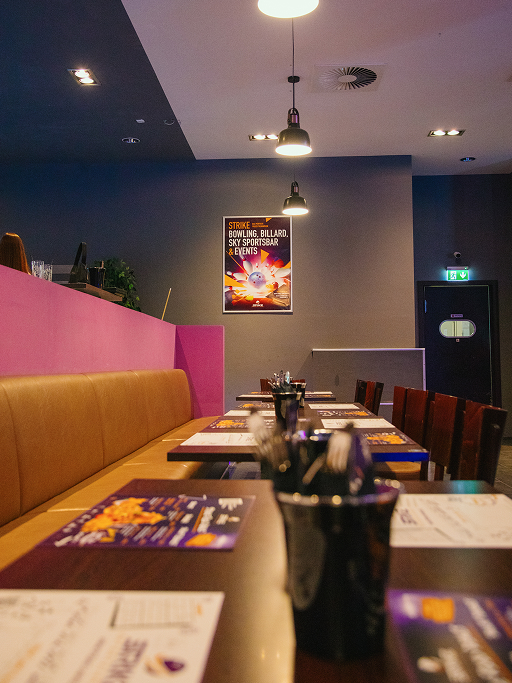 Ihre Firmenfeier im STRIKE Entertainment Center Esstische und Sitzbereiche im Strike Entertainment Center